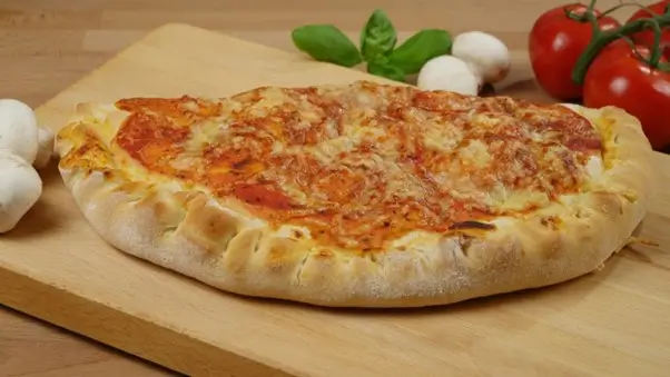 A classic Italian calzone pizza with tomato and cheese on a wooden board