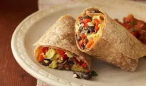 Vegetable burrito filled with fresh bell peppers, avocado, and lettuce, served on a plate
